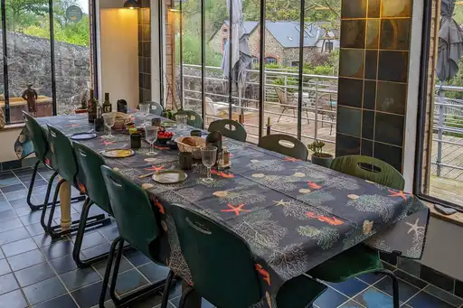 Esstisch im Aufenthaltsraum des Hauses am Flussufer mit großen Fenstern.