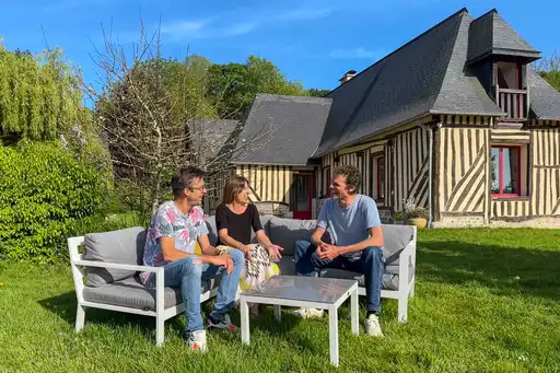 Menschen sitzen auf einer Lounge vor einem Fachwerkhaus in der Normandie