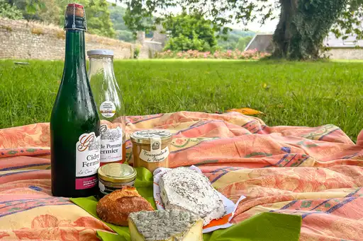 Picknickdecke mir Brot, Käse, Wein im Garten des Landhauses in der Normandie