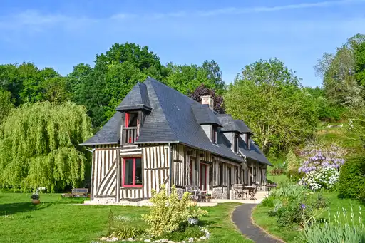 Fachwerkhaus von der Seite mit der Terrasse und Garten in der Normandie