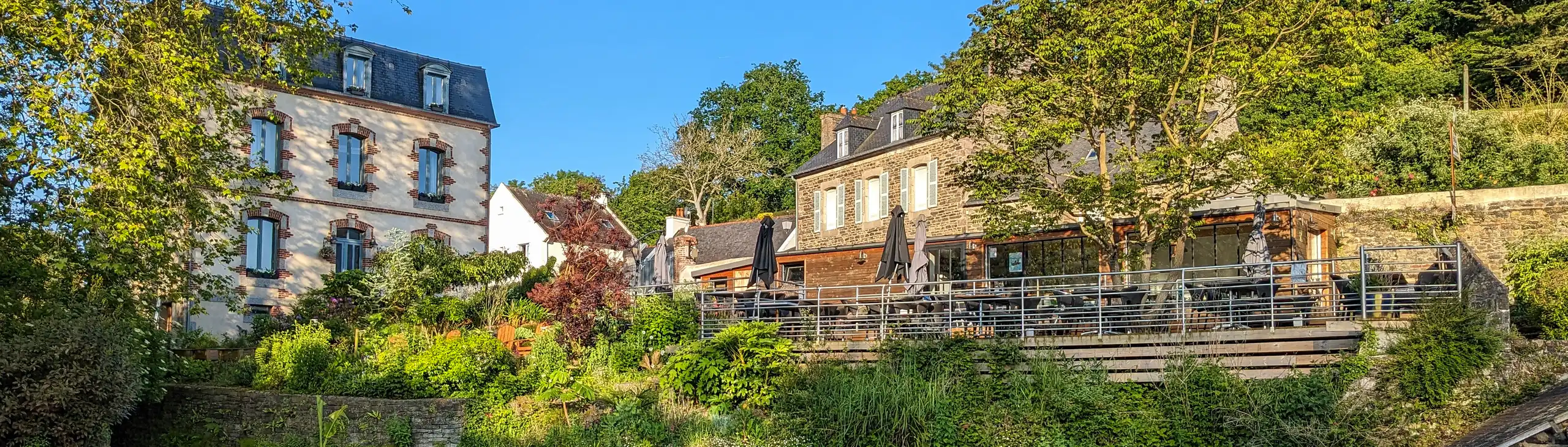 Eine kleine Holzbrücke, die Über den Fluss des Hauses am Flussufer in der Bretagne führt