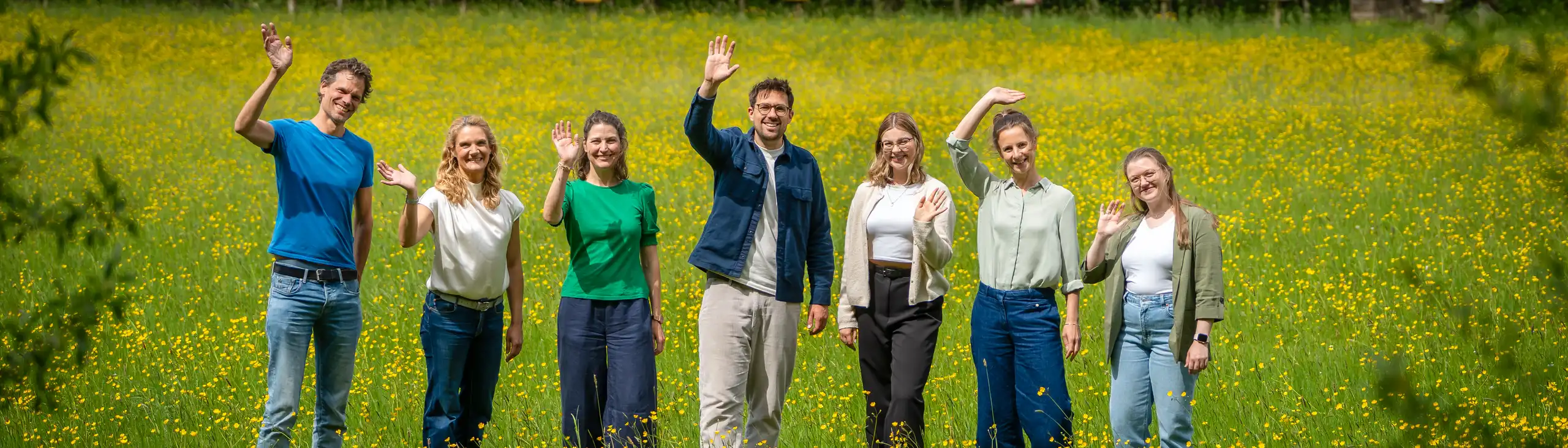 Das Team FN winkend auf der Wiese vor dem Büro