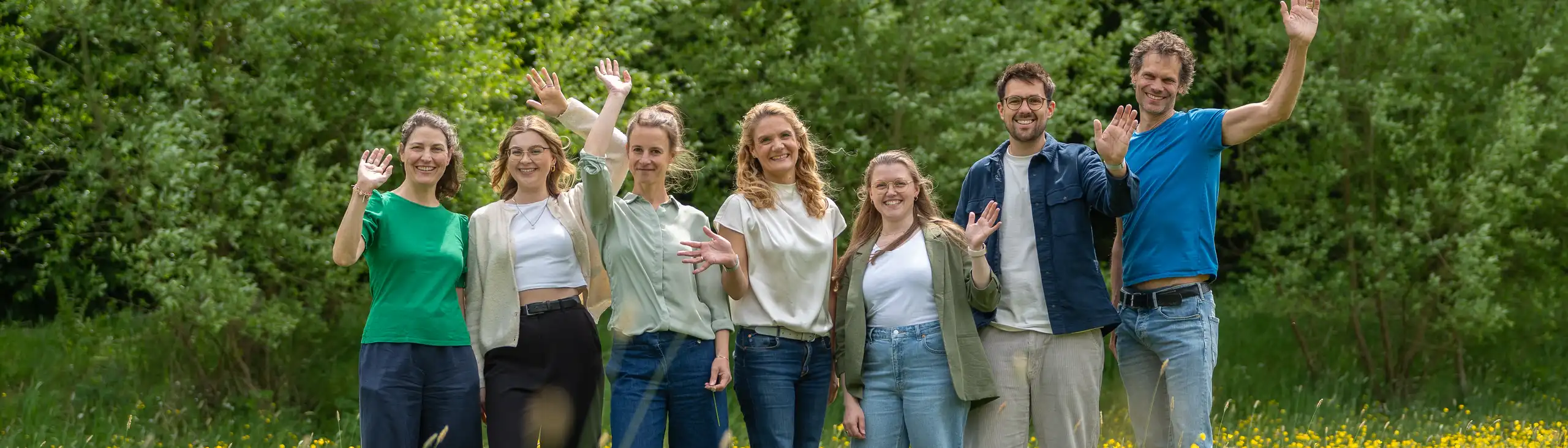 Das Team winkt auf einer Wiese