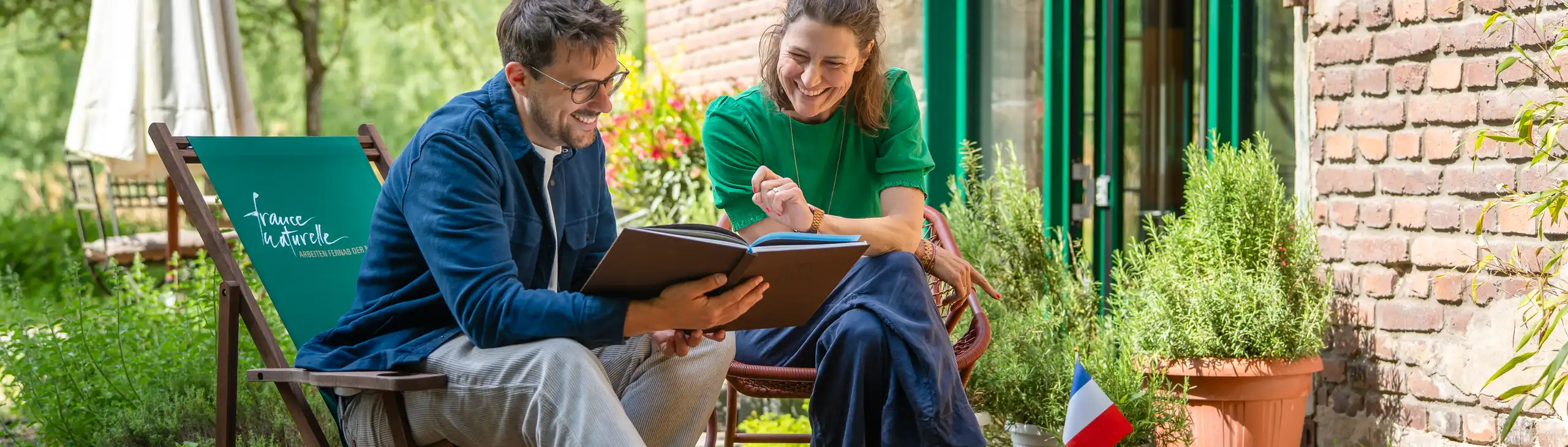 Zwei Personen auf einer Terrasse schauen sich einen Reiseführer an