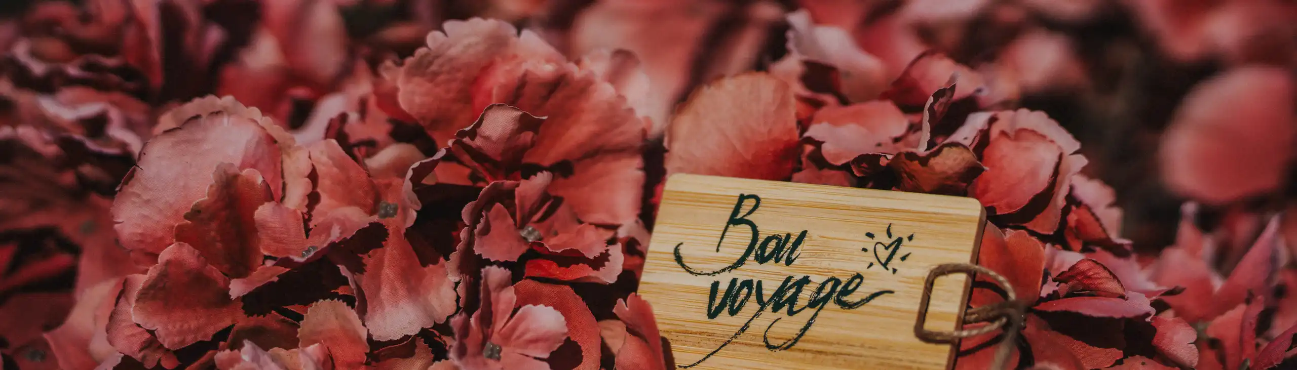 Ein Blumenstrauß in den ein Holzkofferanhänger gesteckt wurde