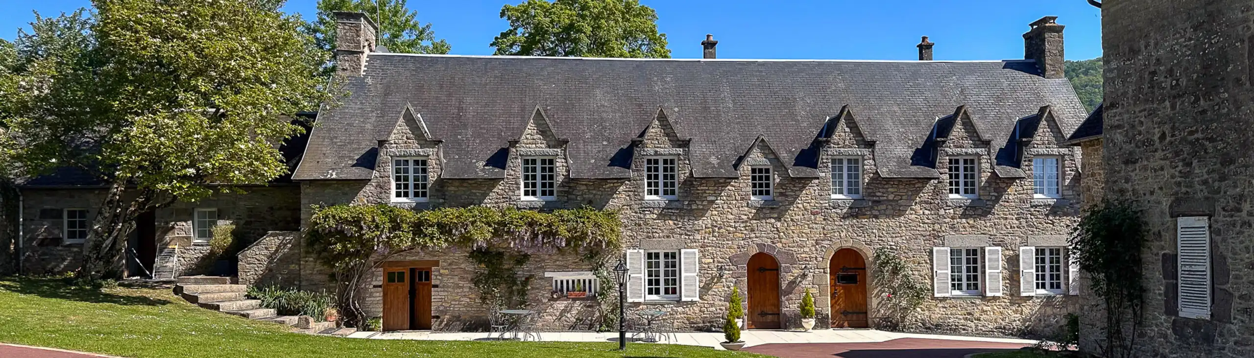 Großer Vorgarten mit einem rotem Weg der zum Haus in der Normandie hinführt