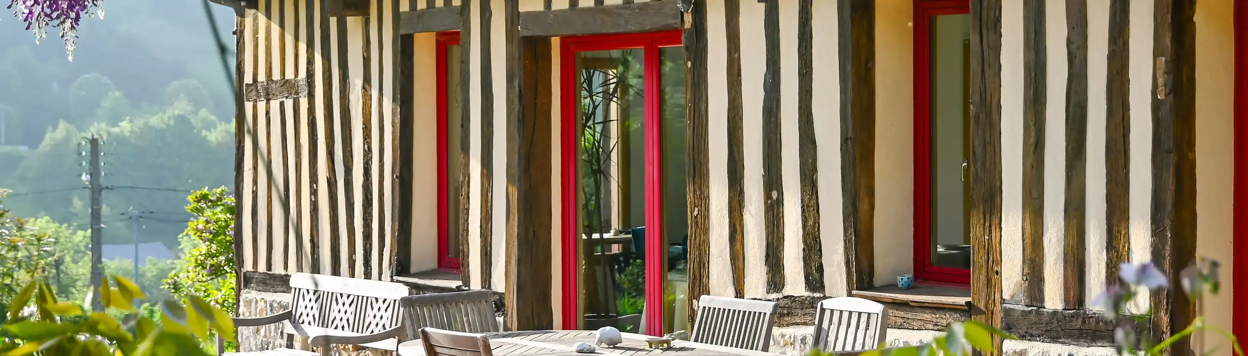 Terrasse mit Tisch und einer Bank vor dem Fachwerkhaus in der Normandie