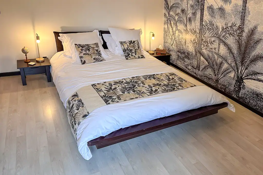 Schlafzimmer mit Bett und floraler Tapete in der Noramndie