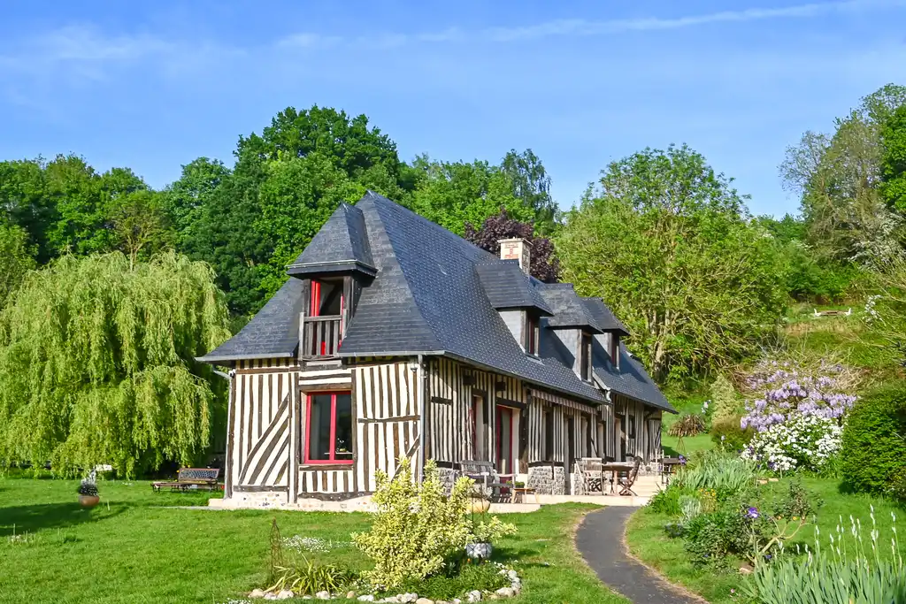 Fachwerkhaus von der Seite mit der Terrasse und Garten in der Normandie