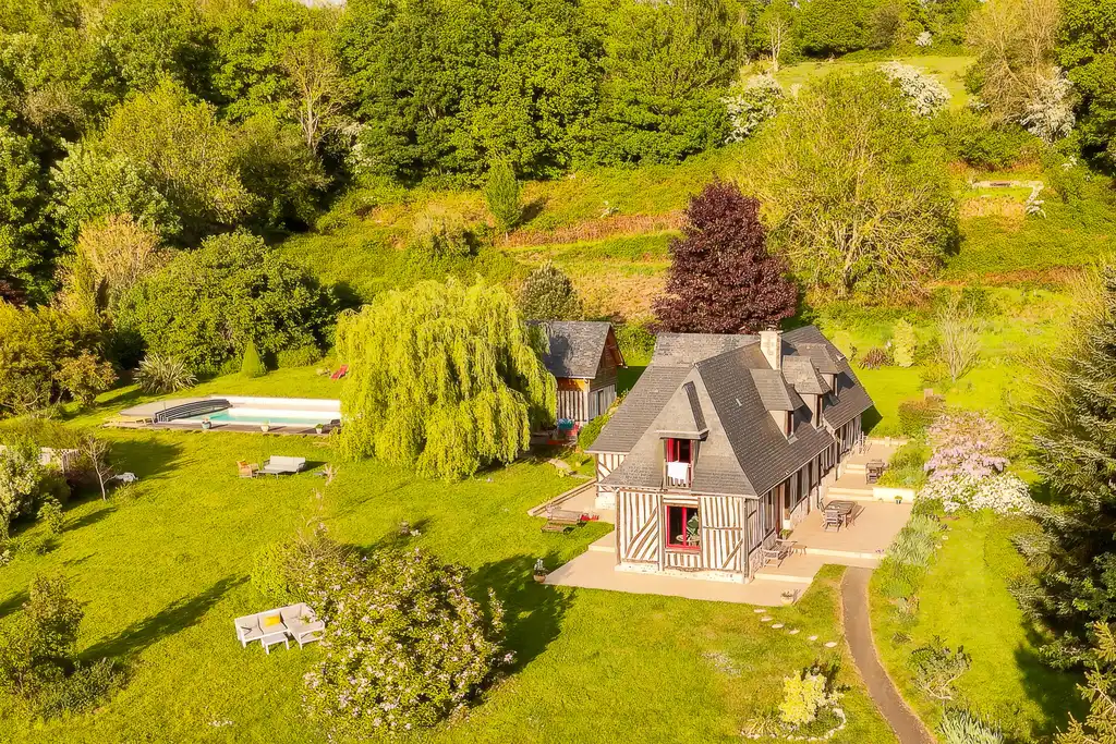 Ein Fachwerkhaus mit Pool inmitten der grünen Landschaft der Normandie