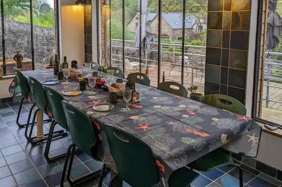 Esstisch im Aufenthaltsraum des Hauses am Flussufer mit großen Fenstern.