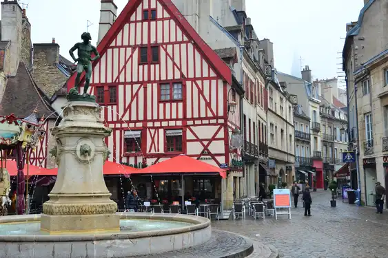 Ein offener Platz in der Stadt von Dijon mit einem Brunnen und einem Fachwerkhaus