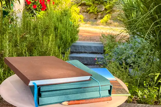 Der Reiseführer samt dem Paket liegen auf einem kleinen Beistelltisch auf der Terrasse im Grünen