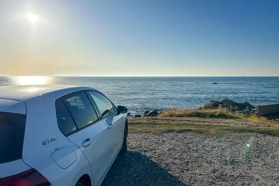 Ein Auto steht auf einem Parkplatz am Meer