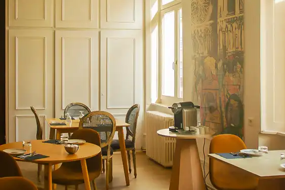 Ein heller, warmer Frühstücksraum mit mehreren Tischen und einer Kaffeeemaschine