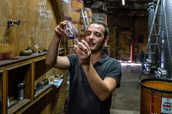 Ein Winzer im Burgund der seinen Wein im Weinglas begutachtet