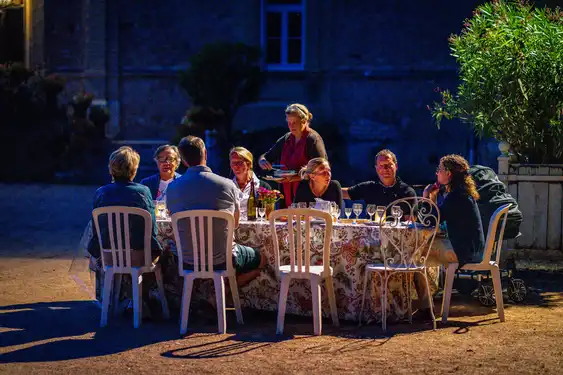 Gäste die gemeinsam im Garten einer Unterkunft im Burgund ein Abendessen genießen