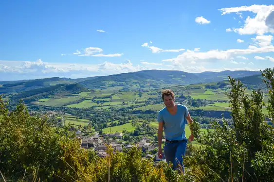 Thomas steht vor einem Ausblick über Felder und Berge im Burgund