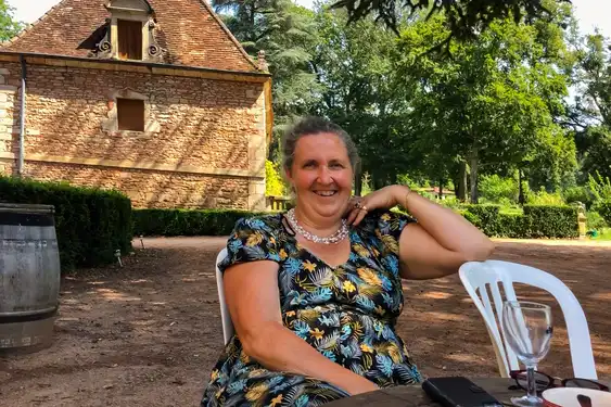 Die Gastgeberin sitzt im Garten des Schlosses im Burgund an einem Tisch