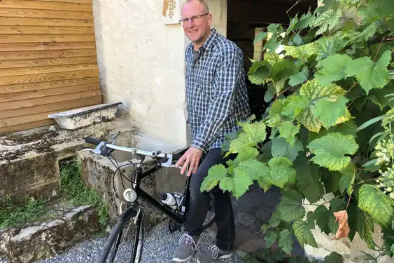 Der Gastgeber des Tuffsteinhauses in der Loire steht mit seinem Fahrrad