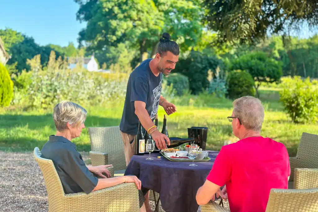 Ein Mann schenkt einem Paar Wein ein