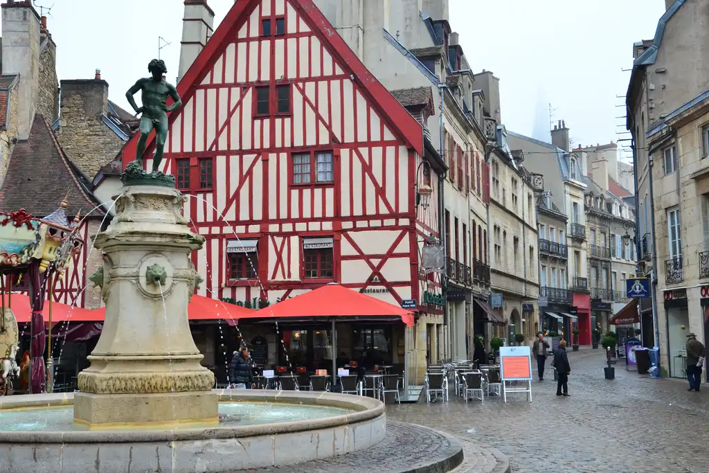 Ein offener Platz in der Stadt von Dijon mit einem Brunnen und einem Fachwerkhaus