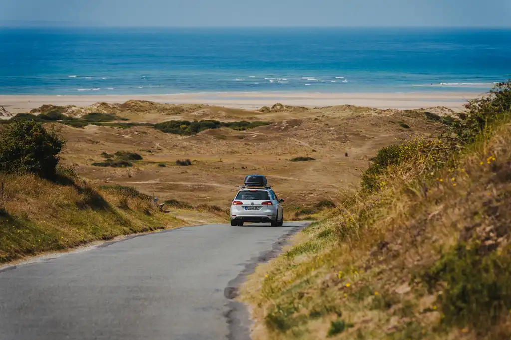 Ein Auto fährt über eine Landstraße zum Strand in der Normandie