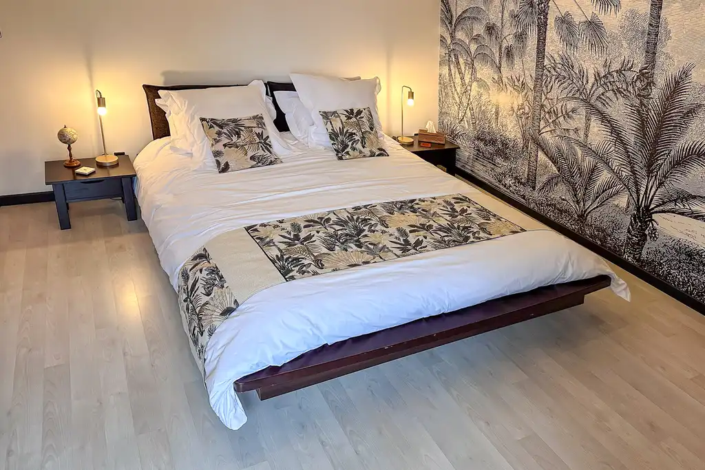 Schlafzimmer mit Bett und floraler Tapete in der Noramndie