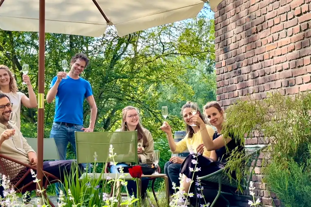 Das Team sitzt auf der Terrasse mit Sektgläsern