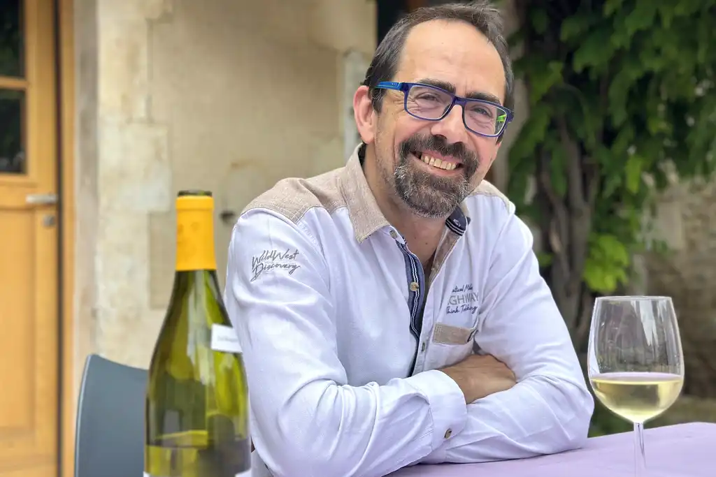 Der Gastgeber der alten Poststation sitzt an einem Tisch mit einem Glas Wein