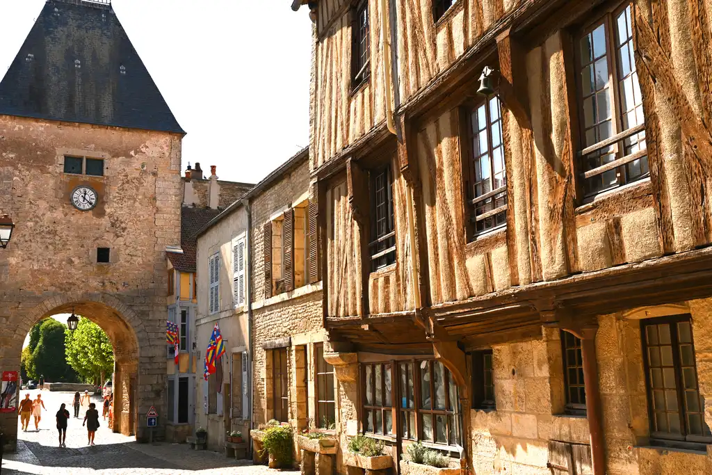Eine Straße in einer Altstadt im Burgund mit Fachwerkhäusern und einem Uhrenturm