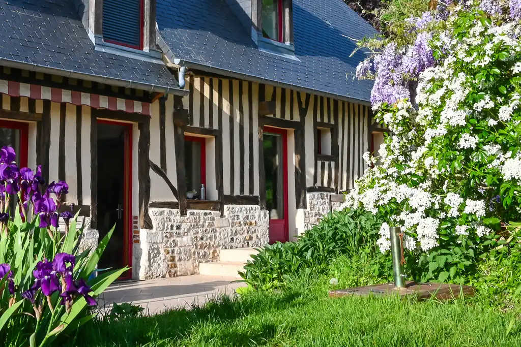 Ein uriges Fachwerkhaus umrahmt von Blumen in der Normandie