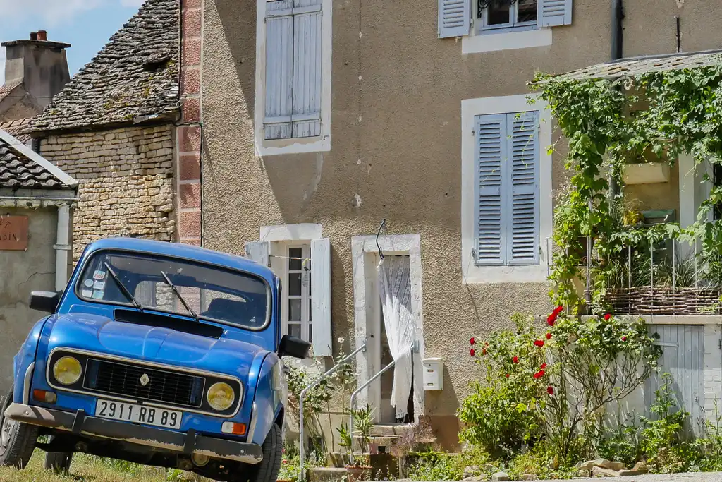Ein altes blaues Auto vor einem charmanten Haus im Burgund