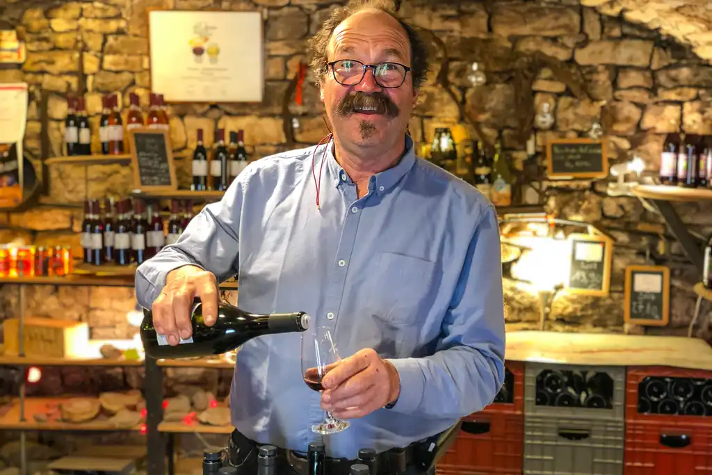 Ein Winzer in einem Weinkeller im Burgund schenkt ein Glas Wein ein