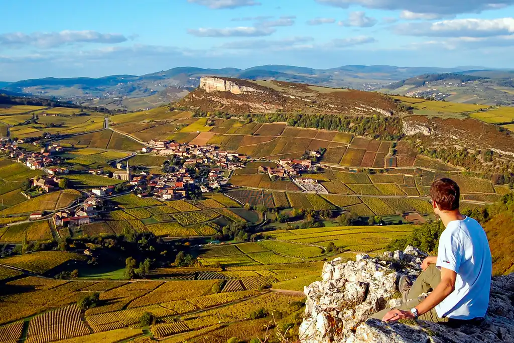 Thomas sitzt auf einem Berg mit Ausblick über die Landschaft im Burgund