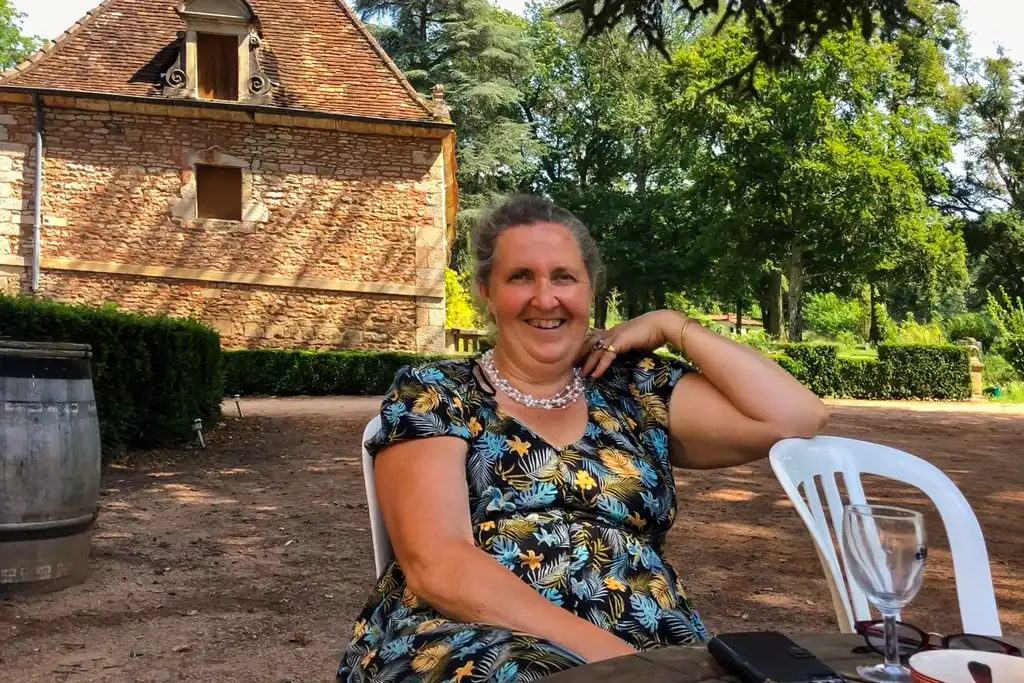 Die Gastgeberin sitzt im Garten des Schlosses im Burgund an einem Tisch