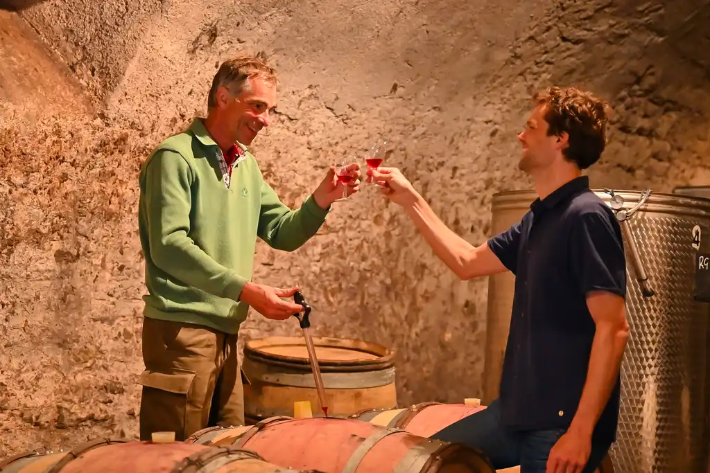 Der Gastgeber des Schlosses im Burgund und Thomas stoßen mit Wein an, im Winzerkeller.