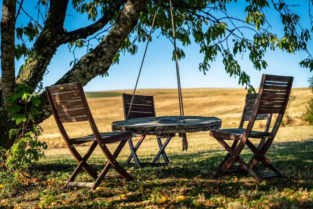 Stühle mit einem Tisch im Schatten eines Baumes vor einem Feld im Burgund