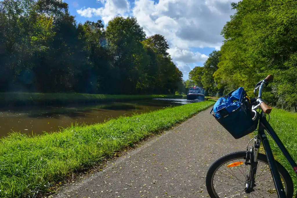 Ein kleiner Fluss im Burgund mit einem Schiff und einem Fahrrad auf dem Weg der entlang des Flusses führt