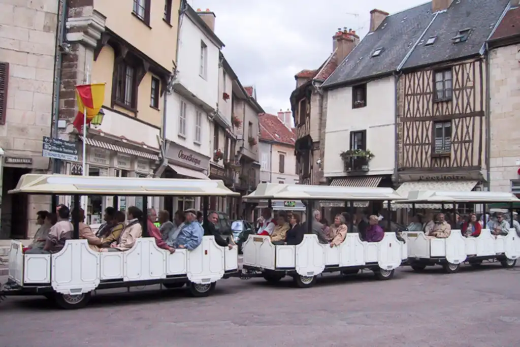 Touristen fahren in einer Wegebahn durch eine Stadt im Burgund