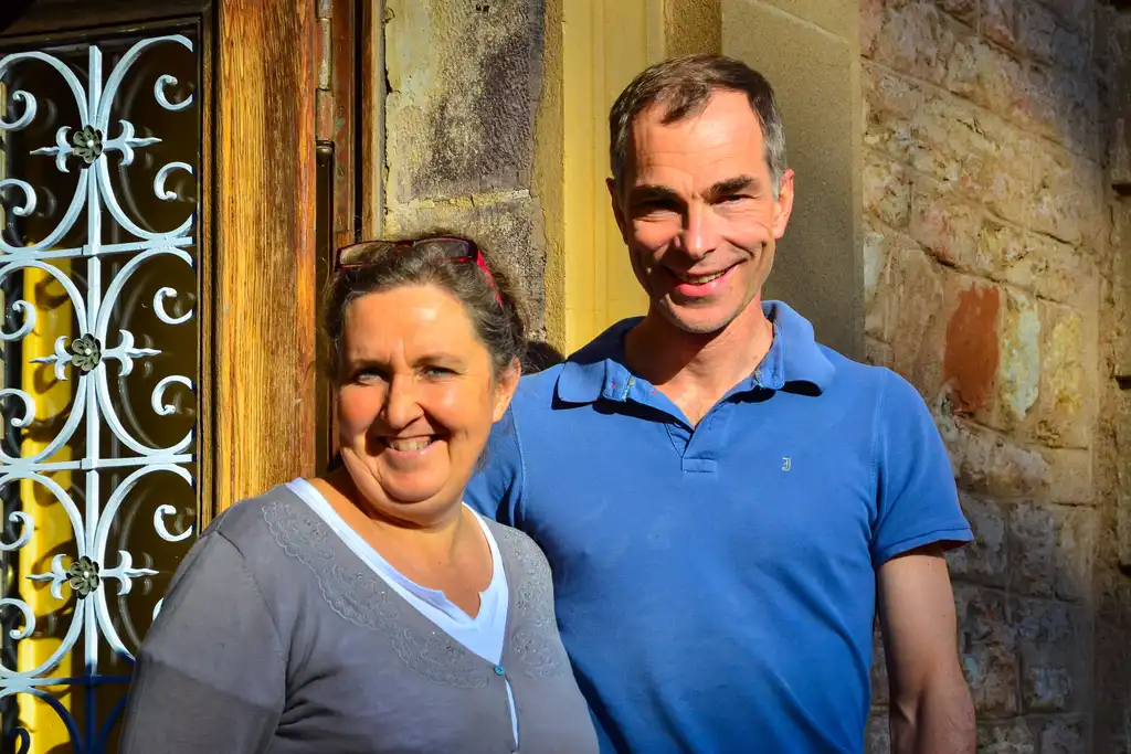 Das Gastgeberpaar des Schlosses im Burgund steht lächelnd im Eingang