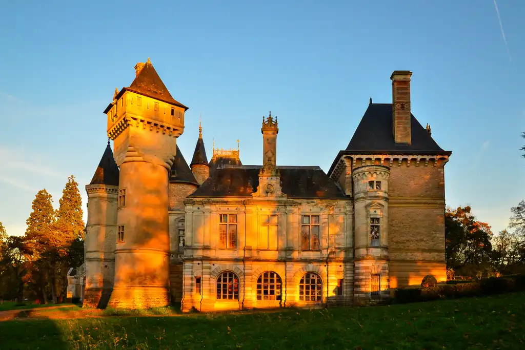 Das Schloss im Burgund wird von orangenen Strahlen der Abendsonne beleuchtet
