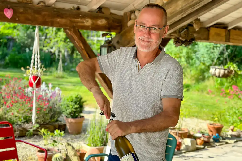 Der Gastgeber des Gutshofes in der Loire öffnet im Garten eine Flasche Wein