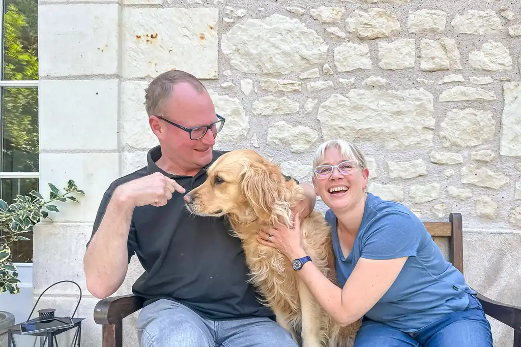 Das Gastgeber sitzten mit ihrem Hund auf der Bank vor dem Tuffsteinhaus in der Loire