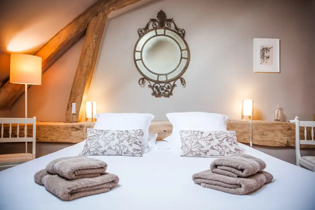 Ein rustikales Gästezimmer im Gutshof in der Loire mit sorgfältig gefalteten Handtücher auf dem Bett