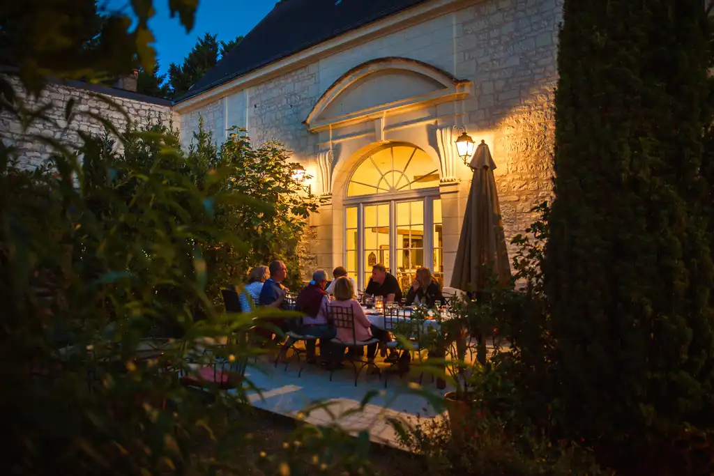 Die Gäste essen an einem Tisch im Innenhof des Tuffsteinhauses in Loire