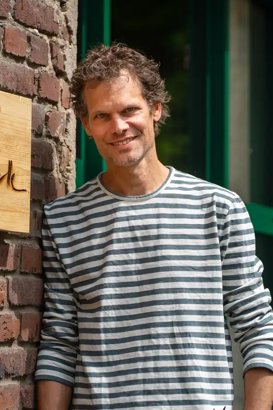Thomas vor dem Büro an einer Wand gelehnt