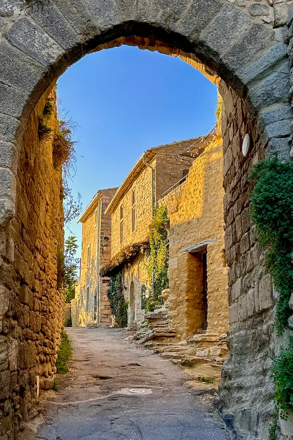 Ein alter Steinbogen der in eine kleine Gasse eines Dorfes in der Provence führt