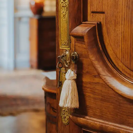 Eine geöffnete Holztüre mit Schlüssel und goldenen Ornamenten