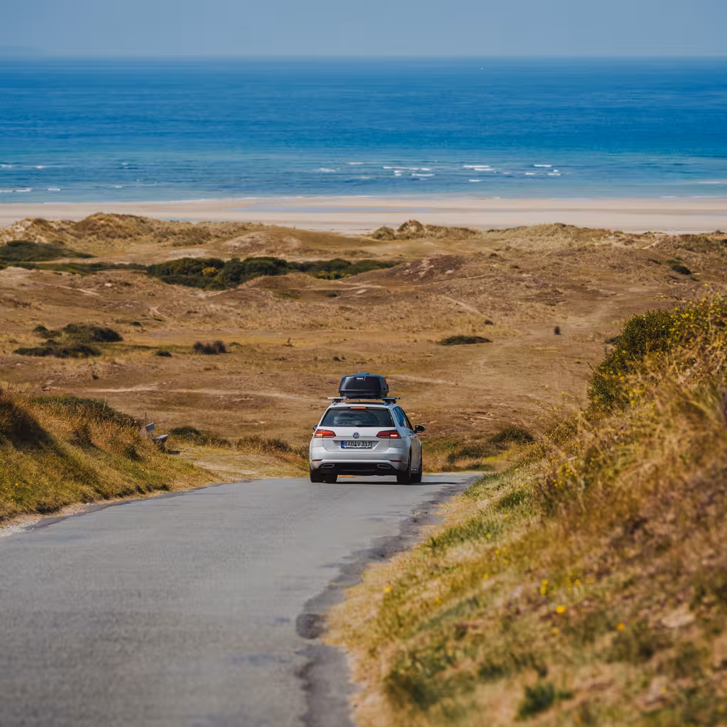Ein Auto fährt über eine Landstraße zum Strand in der Normandie